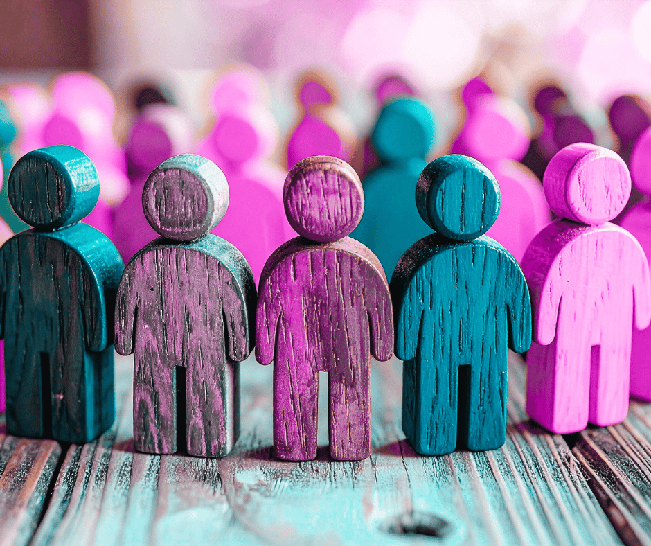 An image of wooden people symbolising male and female straight spouses gathering during Pride for support